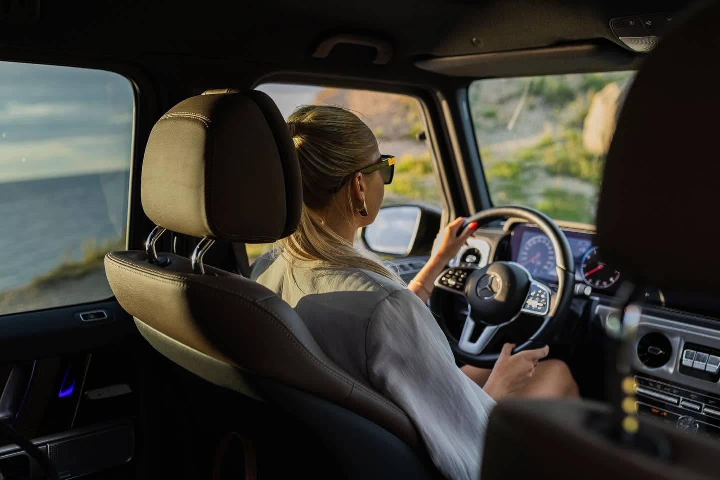 A driver at the wheel of a Mercedes-Benz G-Class on a test drive by the sea